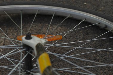 Görüntü, görünürlüğü ve güvenliği arttıran parlak turuncu yansıtıcıyı içeren bir bisiklet tekerleğinin detaylı yakın çekimini gösteriyor.