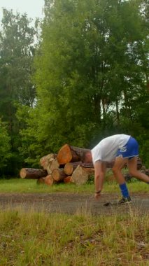 Kararlı bir adam dışarıda, kütüklerin önünde şınav çeker. Gücünü ve adanmışlığını gösteriyor. Nefesini tutuyor. Güzel, doğal bir arka planda.