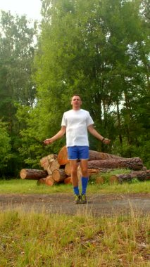 Bir adam enerjik atlama ipi egzersizleri sergiliyor. Manzaralı dış mekanlarda, çeviklik ve taşralı arka planlara karşı coşku göstererek.