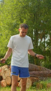 Bu videoda, bir adam çevikliğini ve uygunluğunu, beyaz gömlek ve mavi şort giymiş, rustik bir kütük zeminine ip atlayarak gösteriyor.