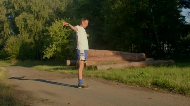 Bir video, doğa yürüyüşünden, koşmaktan, ip atlamaktan hoşlanan, spor yapmayı teşvik eden bir adamı gösteriyor. Bir çocuk beceri göstererek paten kayar ve adamın sonu kaykay olur.