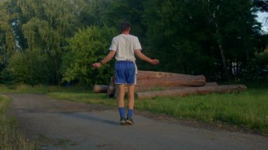 Videoda doğayı seven bir adam, patikalar boyunca koşuyor, manzaralarda yürüyor, ip atlıyor, spor salonunu dışarıdaki sükunetle harmanlıyor.