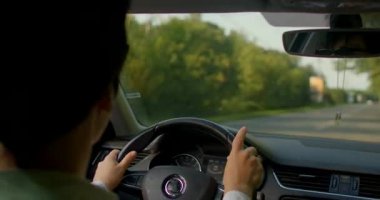 Bir erkek ve bir kadın, kendilerini nefes kesen manzaraya daldıran ve maceraperest hisseden, resimli bir köy yolunda araçlarında geziniyorlar.