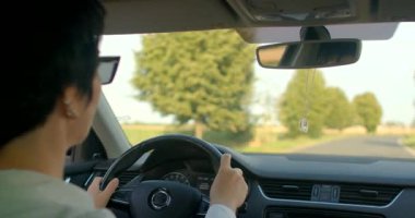 Yeşilliklerle çevrili pitoresk bir kır yolundan geçen bir adam. Asfalttaki lastiklerin sesi doğayı keşfetme zevkini arttırır.