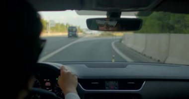 Güneşli bir otoyolda seyahat eden bir adam dikiz aynasına bakıp seyahat ve içgözlem özgürlüğü ve macerayı yansıtır.