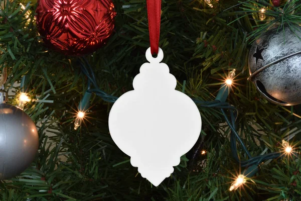 Closeup of vintage ornament dancing from the branch of a lit-up Christmas tree.