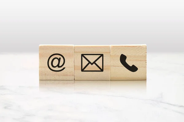 Three wooden blocks with contact us symbols in a minimalist classy marble background.