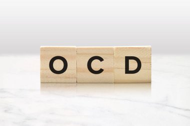 Three wooden tiles spelling OCD against a classy white marble background. clipart
