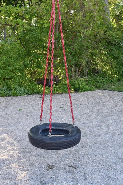 Closeup of empty vintage tire swing at a park on a warm sunny spring day.