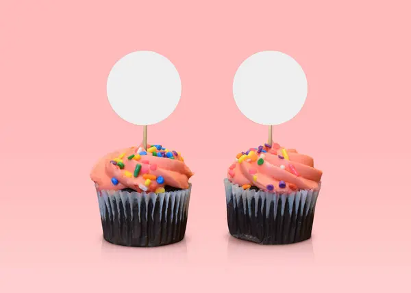 2つの甘いピンクフロストチョコレートカップケーキは 柔らかいピンクの背景に魅了されています — ストック写真