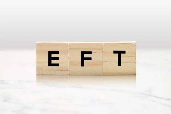 Wooden Tiles spelling out EFT on a minimalist marble backgound. Emotion Focused Therapy concept and Emotional Freedom Technique Concept.