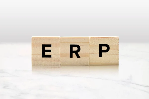 Closeup of wooden tiles spelling out ERP atop a classy white marble tabletop. Exposure and response prevention therapy concept and enterprise resource planning business and marketing concept.