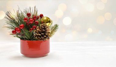 Çam kozalaklarıyla, kızılcıklarla ve beyaz bokeh ışıklarıyla çevrili süslemelerle Noel kutlaması. Bir sürü eşzamanlı alan.