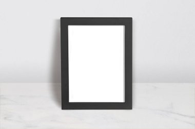 Mermer üzerine siyah çerçeveli yüksek kaliteli poster modeli, markalaşma, ürün gösterimi veya tasarım sunumu için mükemmel.