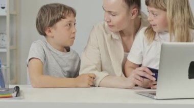 Mother and two children are sitting in from of PC. High quality 4k footage