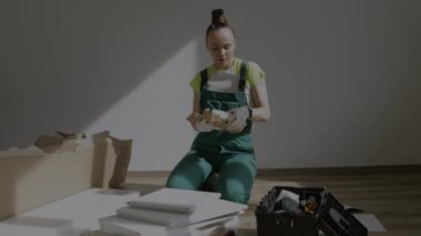 Young female is assembling a piece of furniture. High quality 4k footage