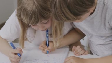 Boy of 9 years old helps his younger sister to make her homework. High quality 4k footage