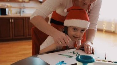 Kız kardeş, erkek kardeş ve anne Noel döneminde birlikte resim yapıyorlar. Yüksek kalite 4k görüntü