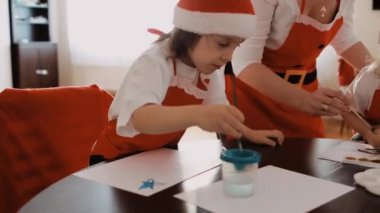 Kız kardeş, erkek kardeş ve anne Noel döneminde birlikte resim yapıyorlar. Yüksek kalite 4k görüntü
