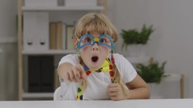 7 yıllık palyaço gözlüğü, kelebek ve pantolon askısı takmış komik bir kız. Yüksek kalite 4k görüntü