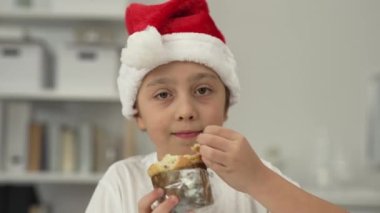 9 yıllık Noel Baba şapkalı çocuk İtalyan Noel tatlı ekmeği yiyor. - Yakın çekim. Yüksek kalite 4k görüntü