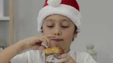 9 yıllık Noel Baba şapkalı çocuk İtalyan Noel tatlı ekmeği yiyor. - Yakın çekim. Yüksek kalite 4k görüntü