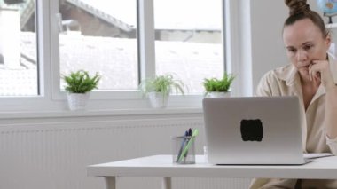 38 yılın yorgun annesi dizüstü bilgisayarda çalışıyor. Arka planda çocuklar oynuyor