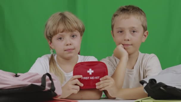 9歳の少年と7歳の少女がテーブルに座り 応急処置キットを見せます 高品質4K映像 — ストック動画