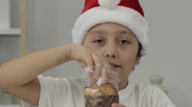 9 yıllık Noel Baba şapkalı çocuk İtalyan Noel tatlı ekmeği yiyor. - Yakın çekim. Yüksek kalite 4k görüntü
