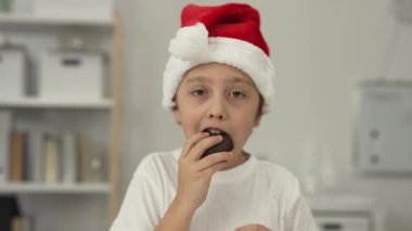 9 yıllık Noel Baba şapkalı çocuk zencefilli ekmek yiyor. - Yakın çekim. Yüksek kalite 4k görüntü