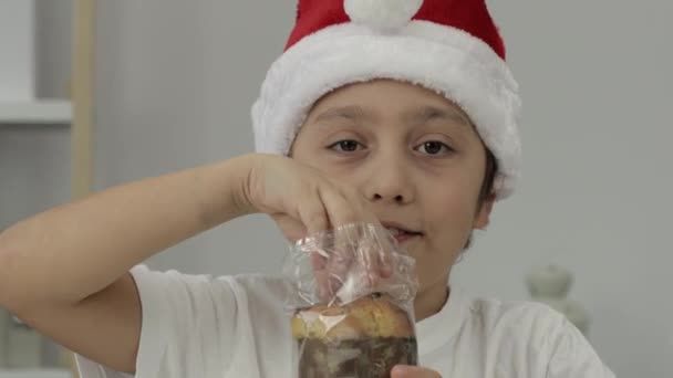 サンタの帽子で9年の男の子はイタリアのクリスマス甘いパンを食べています 閉鎖だ 高品質4K映像 — ストック動画