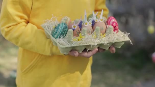 身穿黄色套头衫的7岁女孩把装饰好的复活节彩蛋放在掌心 高质量的4K镜头 — 图库视频影像