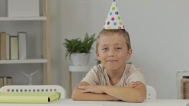 Dokuz yıllık külah şapkalı çocuk masada oturuyor. Yüksek kalite 4k görüntü
