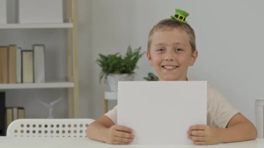 Boy of 9 years in St.Patricks hat is sitting at the table. High quality 4k footage