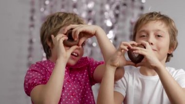 Gingerbread in the shape of hearts in the hands of girl and boy. Medium shot