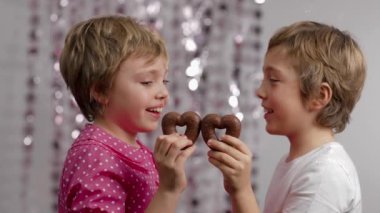 Gingerbread in the shape of hearts in the hands of girl and boy. Medium shot