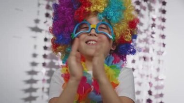 Boy of 10 years old dressed in clowns wig and eyeglasses. He is making applause. High quality 4k footage