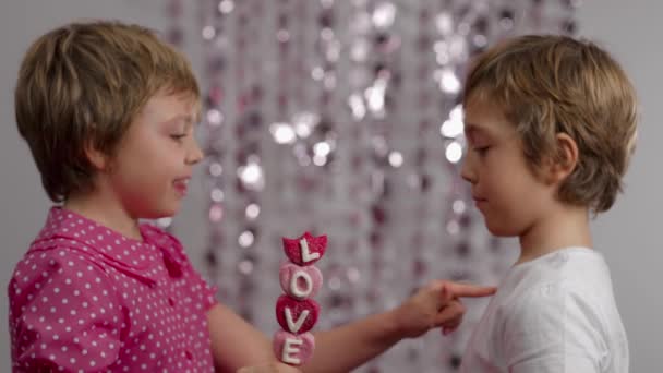 棉花糖的形状的心脏在与男孩说话的女孩的手中 女孩和男孩都不合群 — 图库视频影像