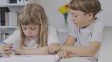 Boy of 9 years old helps his younger sister to make her homework. High quality 4k footage