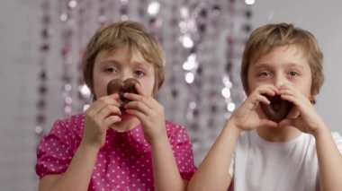 Gingerbread in the shape of hearts in the hands of girl and boy. Medium shot