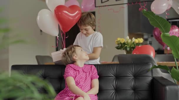 男の子と女の子はバレンタインデーの装飾された部屋のソファにいます 高品質4K映像 — ストック動画
