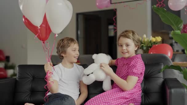 男の子と女の子はバレンタインデーの装飾された部屋のソファに座っています 高品質4K映像 — ストック動画
