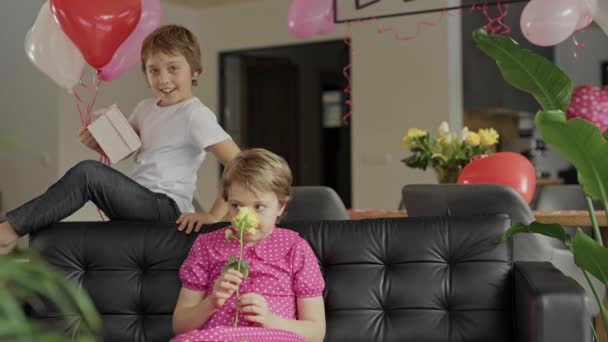 男の子と女の子はバレンタインデーの装飾された部屋のソファにいます 高品質4K映像 — ストック動画