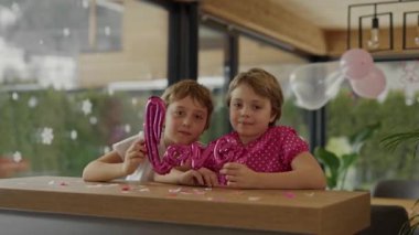 Boy and girl are sitting at the bar table in the decorated room for Valentines Day. Medium shot 