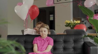 Boy closes the eyes to the girl sitting in the sofa. High quality 4k footage