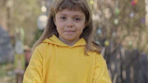 身穿黄色套头衫的7岁女孩把装饰好的复活节彩蛋放在掌心 高质量的4K镜头 — 图库视频影像