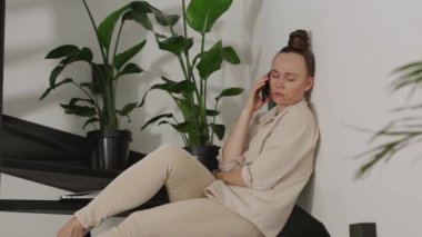 Female speaks on phone sitting on the steel stairs. High quality 4k footage