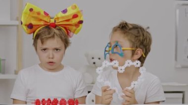 Two children in clowns bow and eye glasses keep two hearts. High quality 4k footage