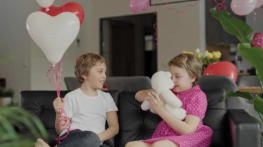 Boy and girl are sitting in the sofa in the decorated room for Valentines Day. High quality 4k footage