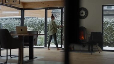 Female between 35 and 40 years is opening the glass door to the garden. High quality 4k footage